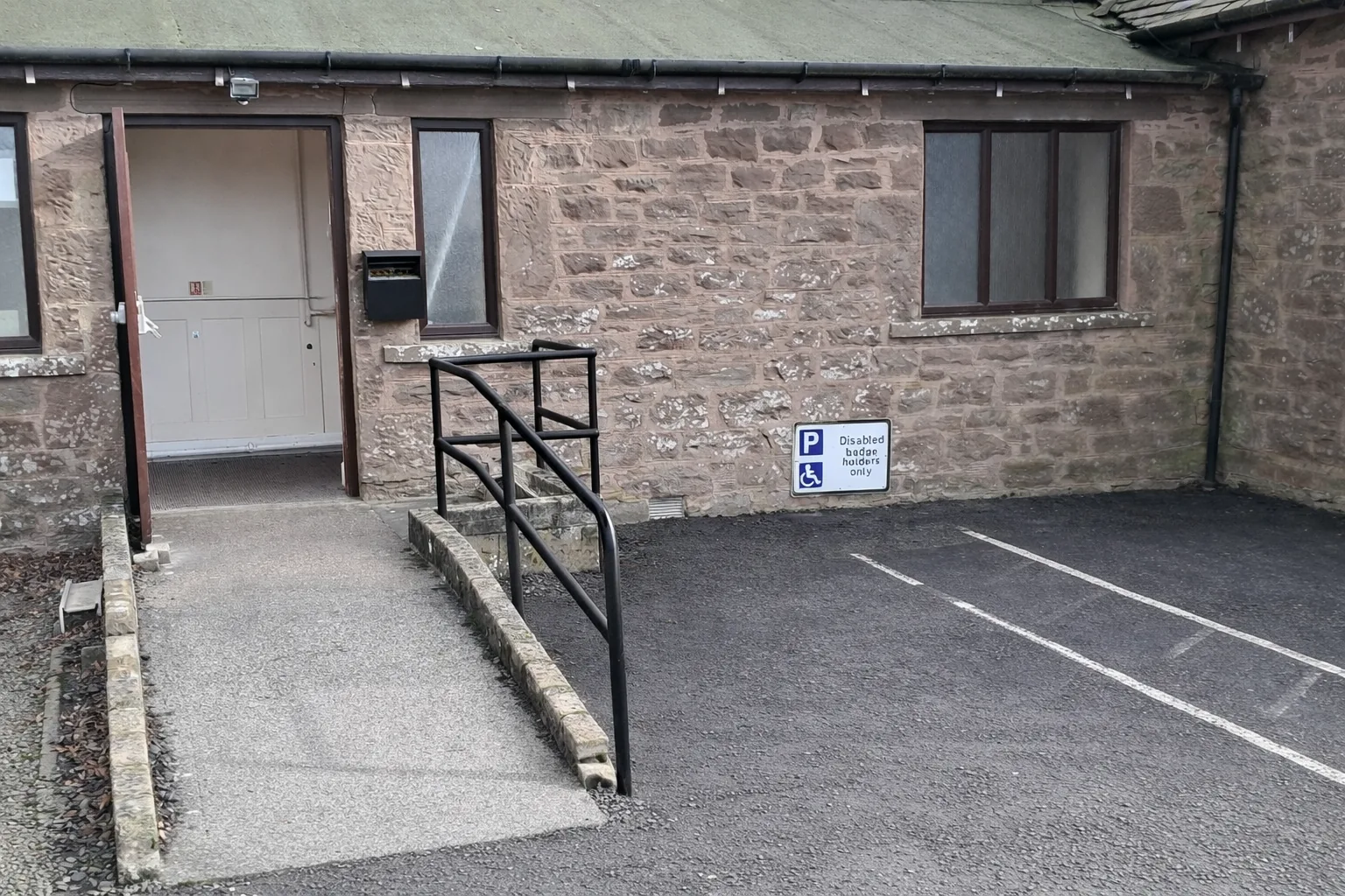 Ramp access adjacent to disabled parking area to the rear of the building