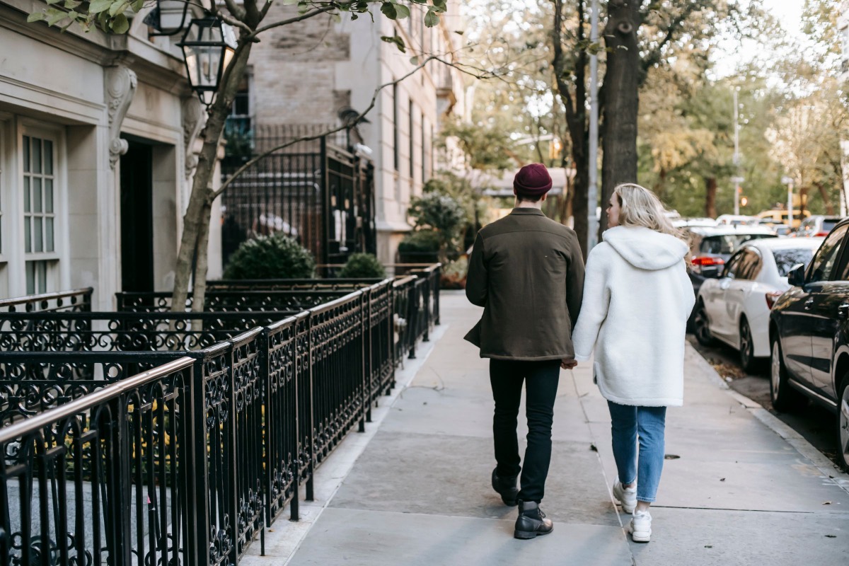 A couple walking together along a tree-lined residential street.