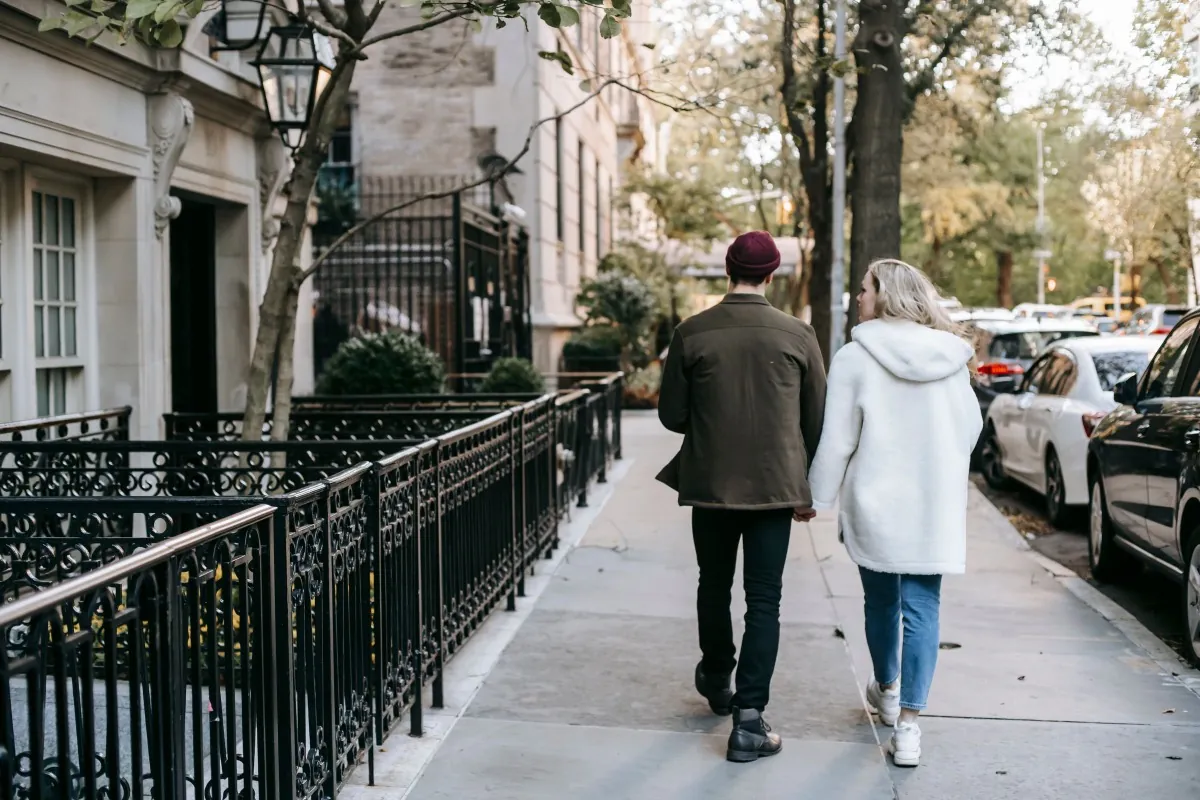 A couple walking together along a tree-lined residential street.