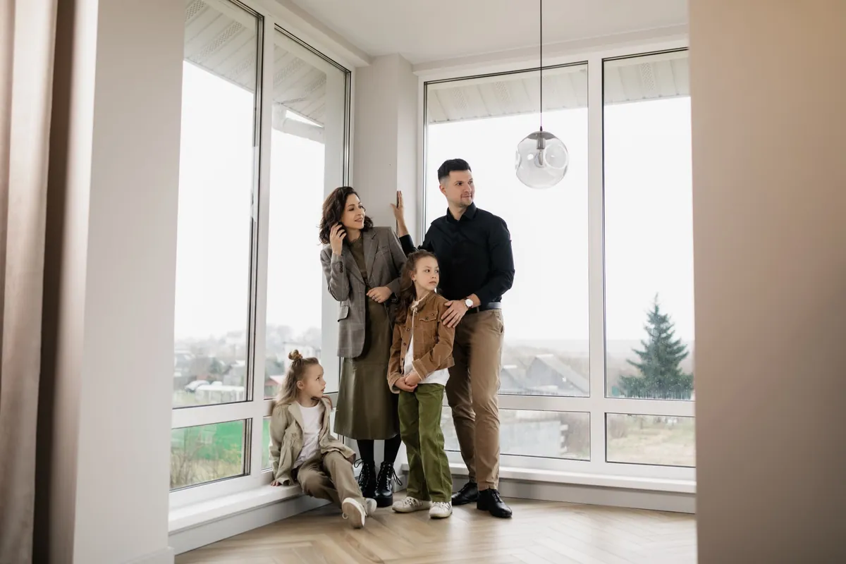 A family at the window of their empty house.